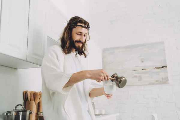 Cheerful Jesus pouring coffee from cezve into cup in kitchen during morning time at home — Stock Photo