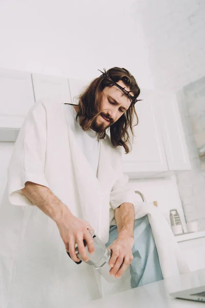 Low angle view of Jesus grinding coffee beans with hands in manual coffeemill in kitchen at home — Stock Photo