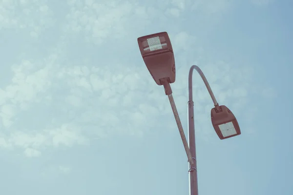 Low angle view of street lamps against blue sky, toned image — Stock Photo