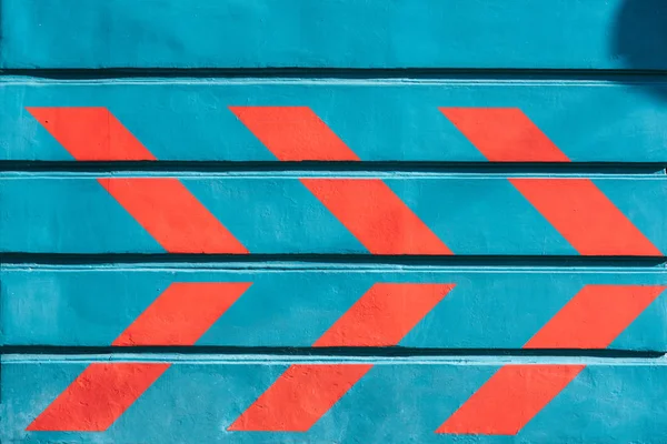 Vista de cerca de las flechas rojas dibujadas en la pared azul exterior - foto de stock