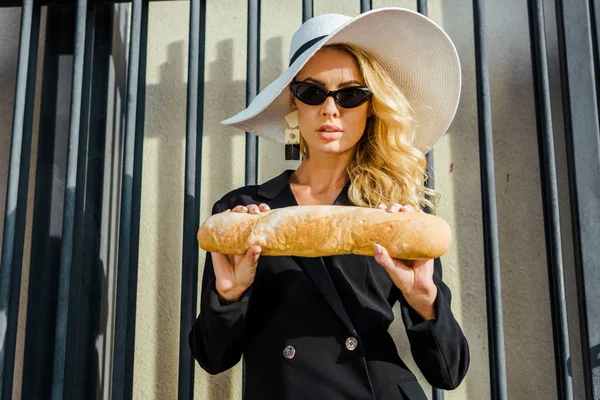 Attraente giovane donna in giacca elegante e cappello in piedi davanti alla recinzione con baguette — Foto stock