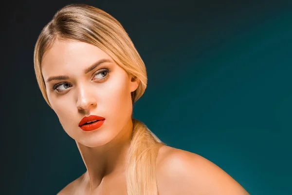 Портрет красивой блондинки с красными губами, смотрящей в сторону на темном фоне — стоковое фото