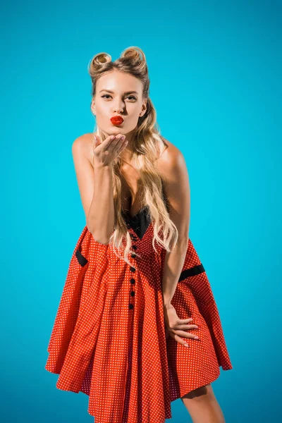 Portrait de femme pin up attrayant dans des vêtements de style rétro soufflant baiser sur fond bleu — Photo de stock