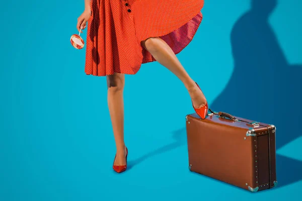 Plan recadré de femme en robe vintage avec sucette et valise sur fond bleu — Photo de stock