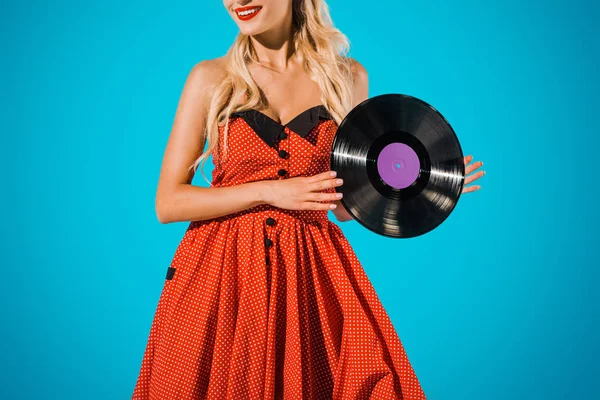 Partial view of woman in vintage dress showing vinyl record on blue backdrop — Stock Photo