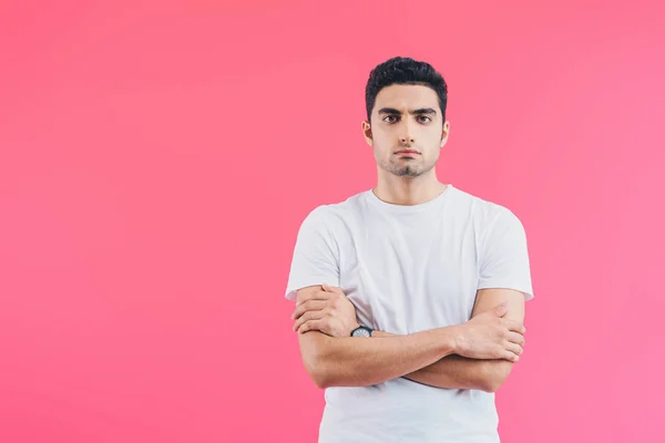 Serious handsome man standing with crossed arms and looking at camera isolated on pink — Stock Photo