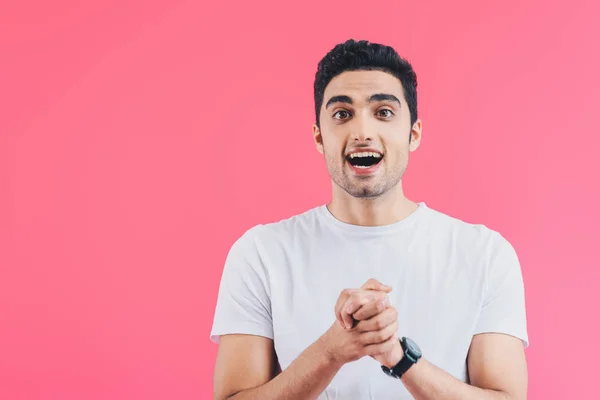 Excitado hombre guapo agarrado de la mano y mirando hacia otro lado aislado en rosa - foto de stock