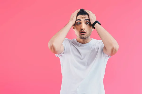 Shocked handsome man touching head and looking at camera isolated on pink — Stock Photo