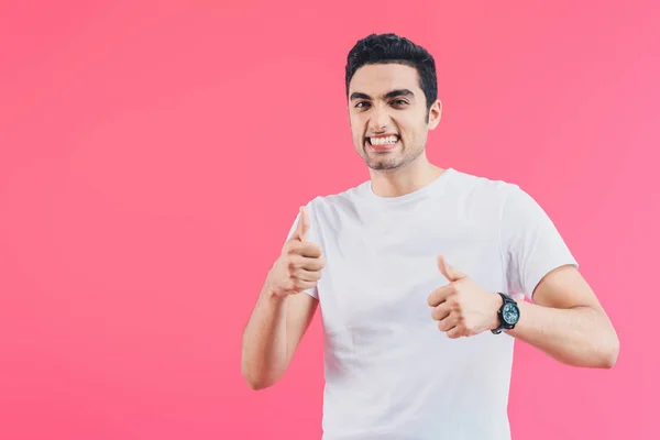 Grimacing smiling man showing thumbs up isolated on pink — Stock Photo