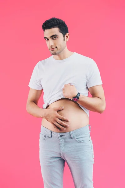 Cheerful handsome man palming belly and looking at camera isolated on pink — Stock Photo