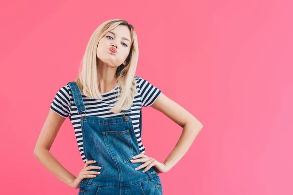 Schöne Mädchen in Jeans insgesamt Grimassen und so tun, als küsste isoliert auf rosa — Stockfoto