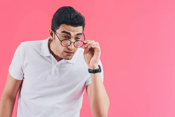 Hombre guapo mirando por encima de gafas aisladas en rosa - foto de stock