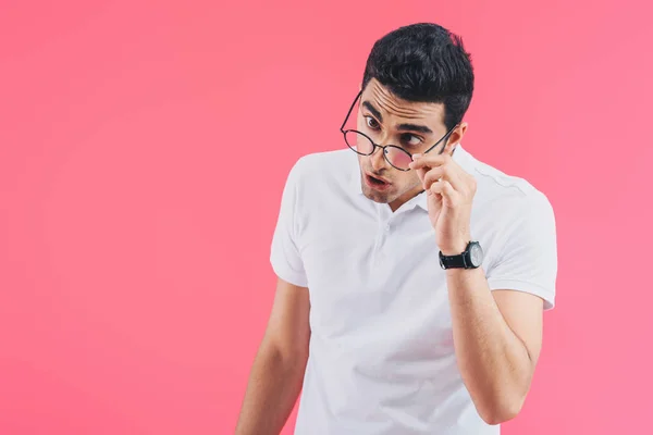 Hombre guapo mueca y tocando gafas aisladas en rosa - foto de stock