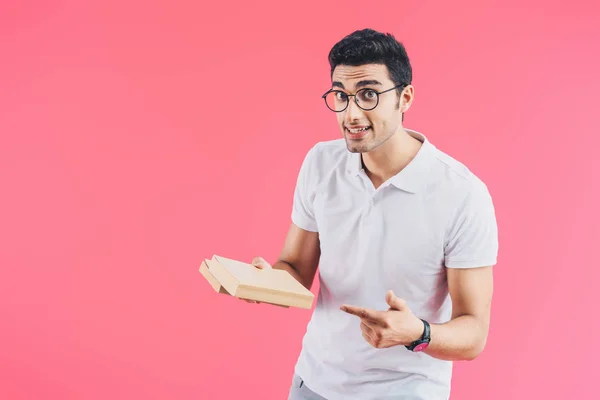 Excited handsome student pointing on books isolated on pink — Stock Photo