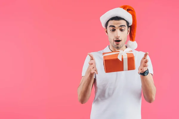 Aufgeregter Mann mit Weihnachtsmannhut fängt Geschenkbox isoliert auf rosa, Neujahrskonzept — Stockfoto