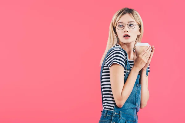 Vista lateral da jovem chocada com café para ir isolado em rosa — Fotografia de Stock