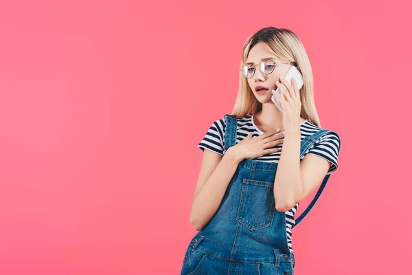 Ritratto di donna emotiva in occhiali che parla su smartphone isolato su rosa — Foto stock