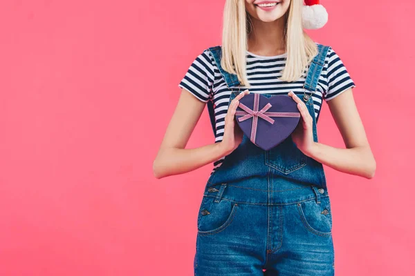 Plan recadré de femme dans le chapeau santa claus avec cadeau en forme de coeur isolé sur rose — Photo de stock