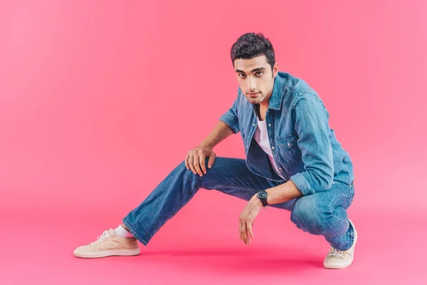 Стильний чоловік позує в джинсовому одязі на рожевому фоні — стокове фото