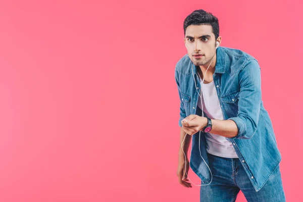 Portrait of young man in casual clothing and earphones isolated on pink — Stock Photo