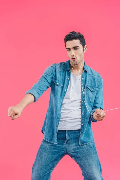 Joven hombre emocional en ropa casual y auriculares bailando aislado en rosa - foto de stock