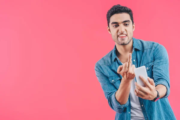 Portrait of angry man showing middle finger to smartphone isolated on pink — Stock Photo