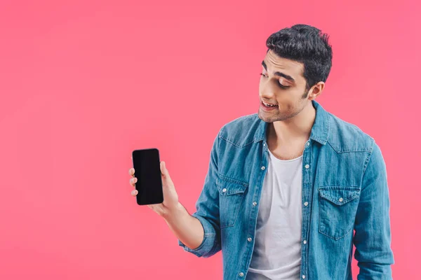 Smiling young man showing smartphone with blank screen isolated on pink — Stock Photo