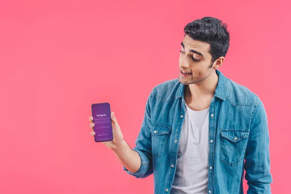 Young man showing smartphone with instagram website isolated on pink — Stock Photo