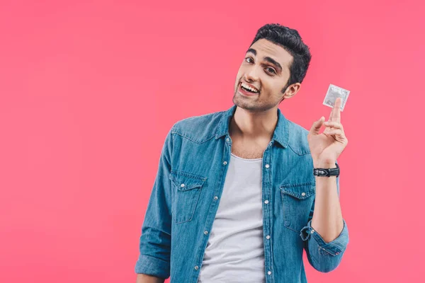 Jovem feliz mostrando preservativo isolado em rosa — Fotografia de Stock