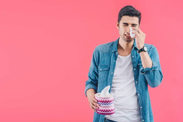 Triste jeune homme avec boîte de tissu pleurant et essuyant des larmes isolées sur rose — Photo de stock