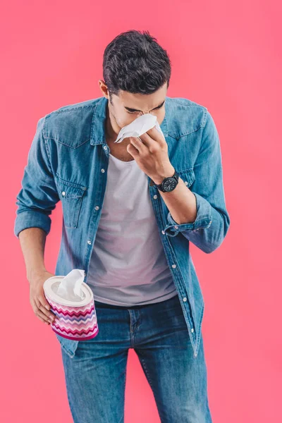 Jeune homme avec boîte de tissu pleurant et essuyant nez isolé sur rose — Photo de stock