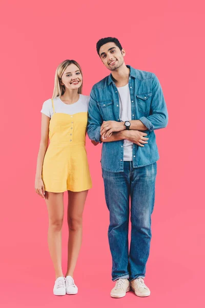 Joyeux jeune couple tenant la main et regardant la caméra isolée sur rose — Photo de stock
