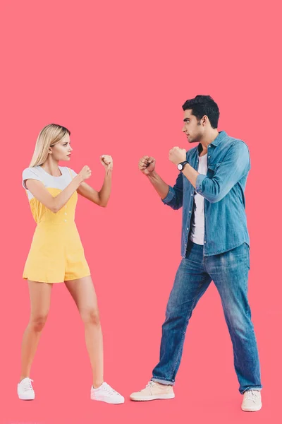 Side view of young couple standing in fight position and looking at each other isolated on pink — Stock Photo