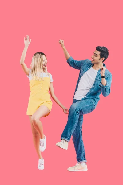 Щаслива молода пара дивиться один на одного і танцює ізольовано на рожевому — стокове фото