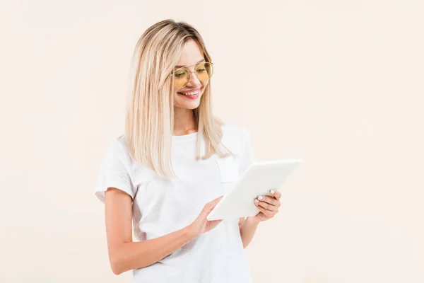 Happy stylish woman in eyeglasses using digital tablet isolated on beige — Stock Photo