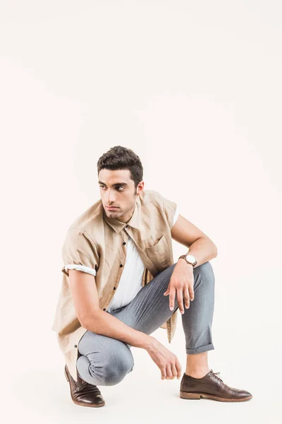 Serious stylish young man in shirt sitting isolated on beige — Stock Photo