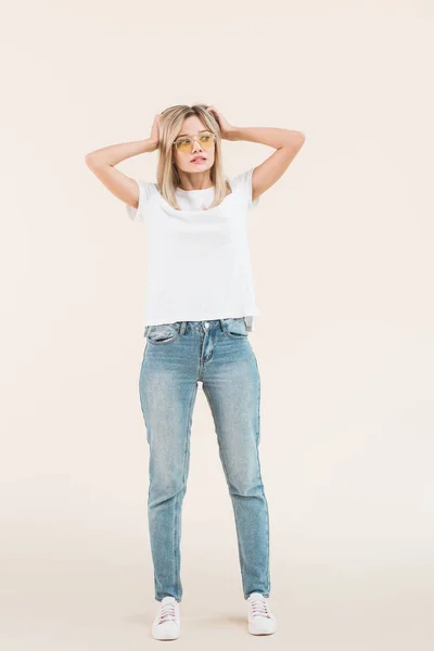 Full length view of young blonde woman in sunglasses looking away isolated on beige — Stock Photo