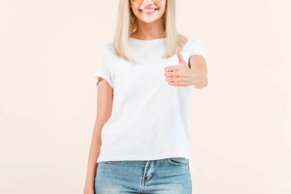Обрізаний знімок усміхненої молодої жінки, що показує великий палець вгору ізольовано на бежевому — стокове фото