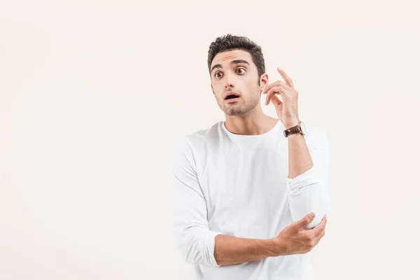 Surprised young man with open mouth looking away isolated on beige — Stock Photo