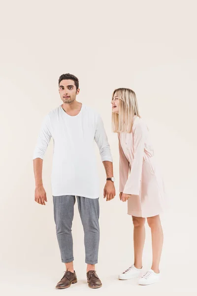 Vista completa de la pareja joven emocional de pie juntos aislados en beige - foto de stock