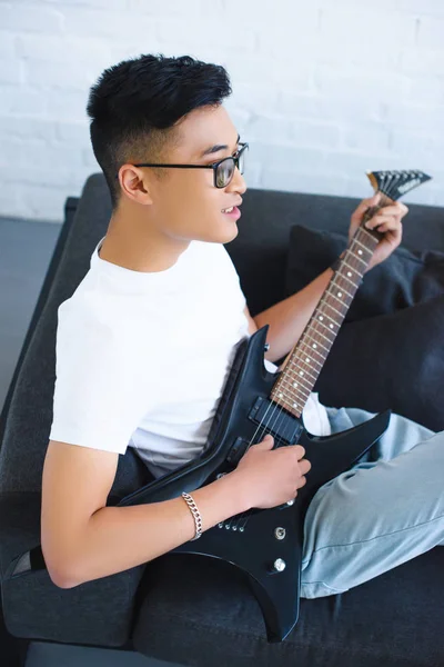 High angle view of handsome asian man playing unplugged electric guitar at home — Stock Photo