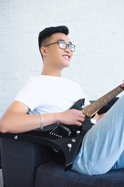 Happy handsome asian guitarist playing unplugged electric guitar at home — Stock Photo