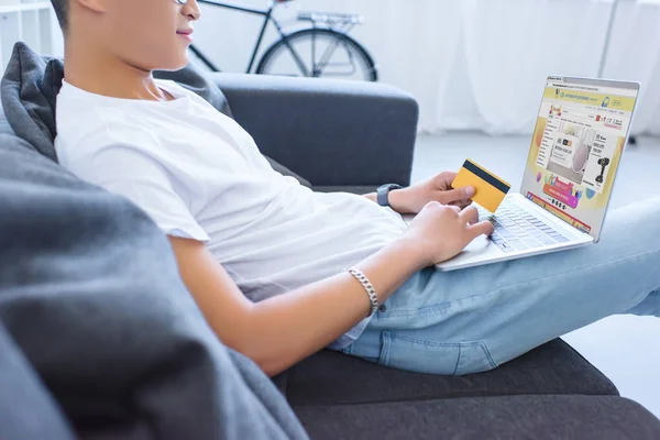 Cropped image of man shopping online with laptop with loaded aliexpress page and credit card at home — Stock Photo