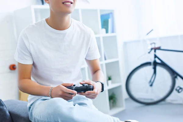 Image recadrée d'un homme souriant jouant à un jeu vidéo sur un canapé à la maison — Photo de stock