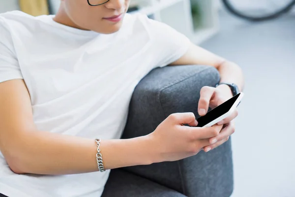 Cropped image of man lying on sofa and using smartphone at home — Stock Photo