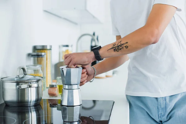 Primo piano vista parziale del giovane tatuato che fa il caffè in cucina — Foto stock