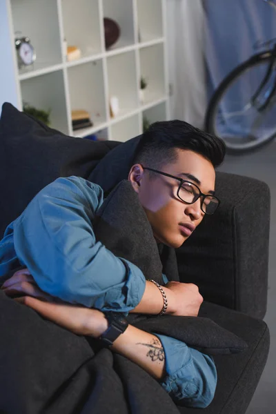 Handsome young asian man in eyeglasses sleeping on sofa at home — Stock Photo