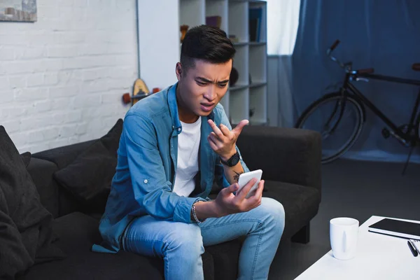 Young asian man using smartphone and giving middle finger — Stock Photo