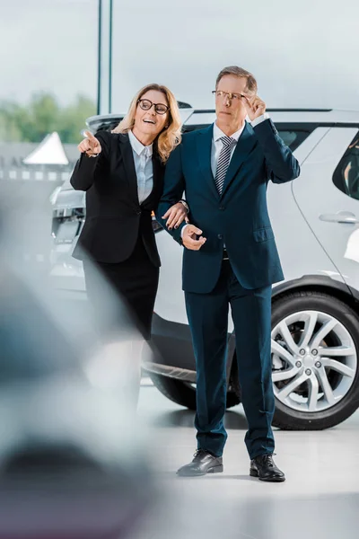 Businessman and businesswoman choosing new automobile in showroom — Stock Photo