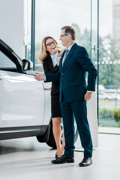 Cheerful business couple looking for new automobile in dealership salon — Stock Photo